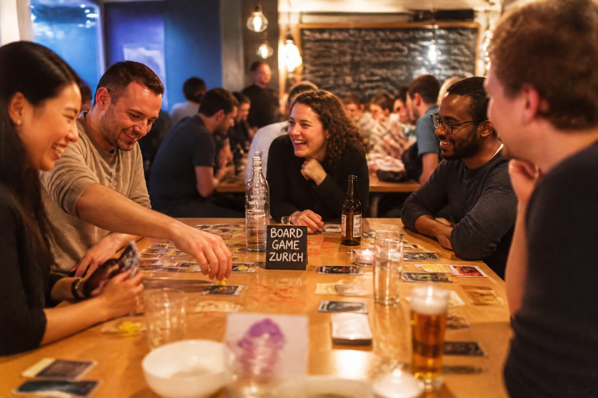 Guests laughing around a table during a ZFG social games night in Zurich